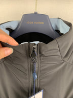Dark gray hooded jacket neckline with zip pull and Louis Vuitton label in view.