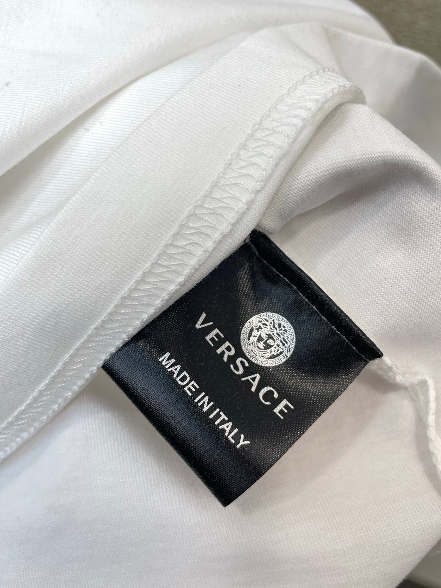 White T-shirt fabric with Versace tag reading Made in Italy