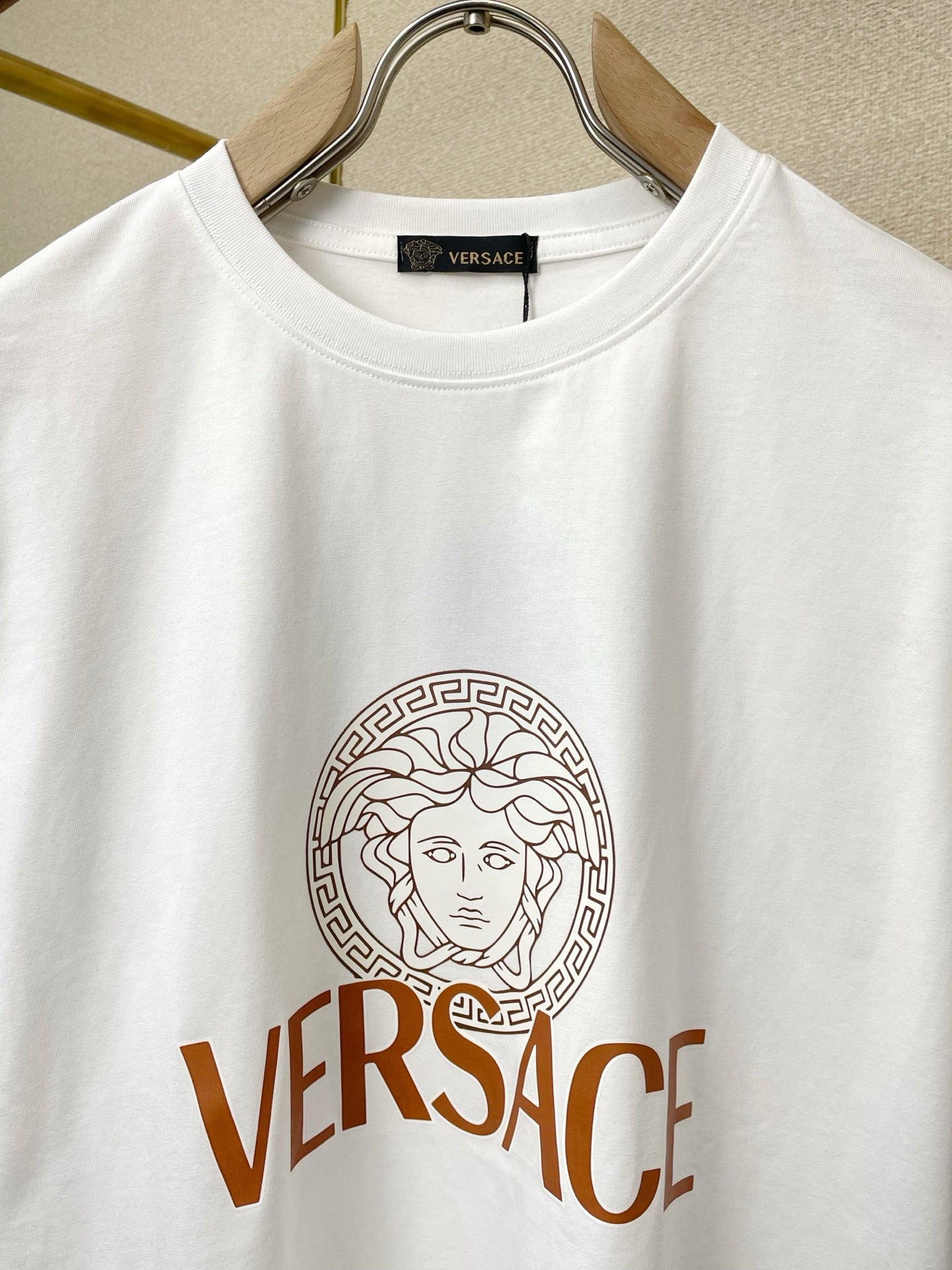 White crewneck T-shirt close-up: Medusa emblem and VERSACE text print