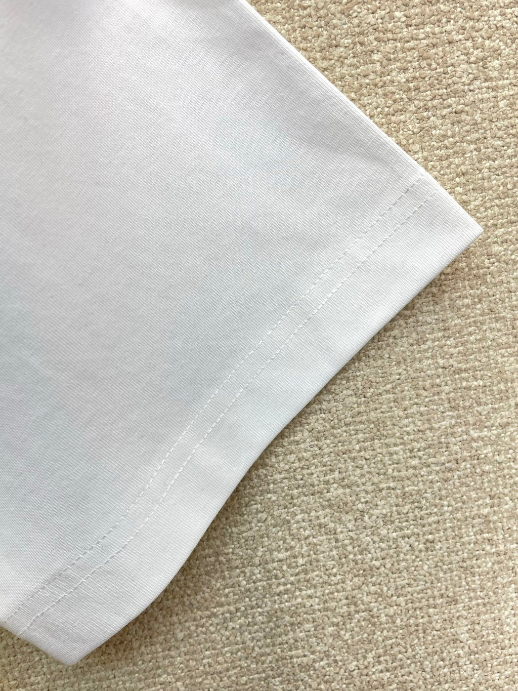 White T-shirt sleeve hem with visible stitching.