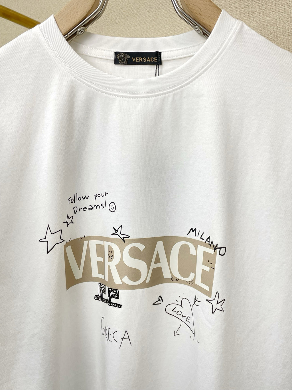 White Versace graphic T-shirt with text and stars print, crew neck, short sleeves.