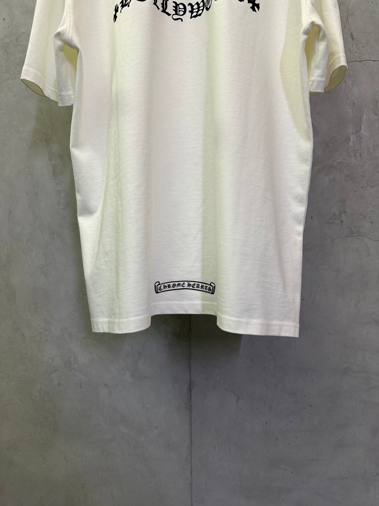 White short-sleeve T-shirt with small hem label at the lower back.