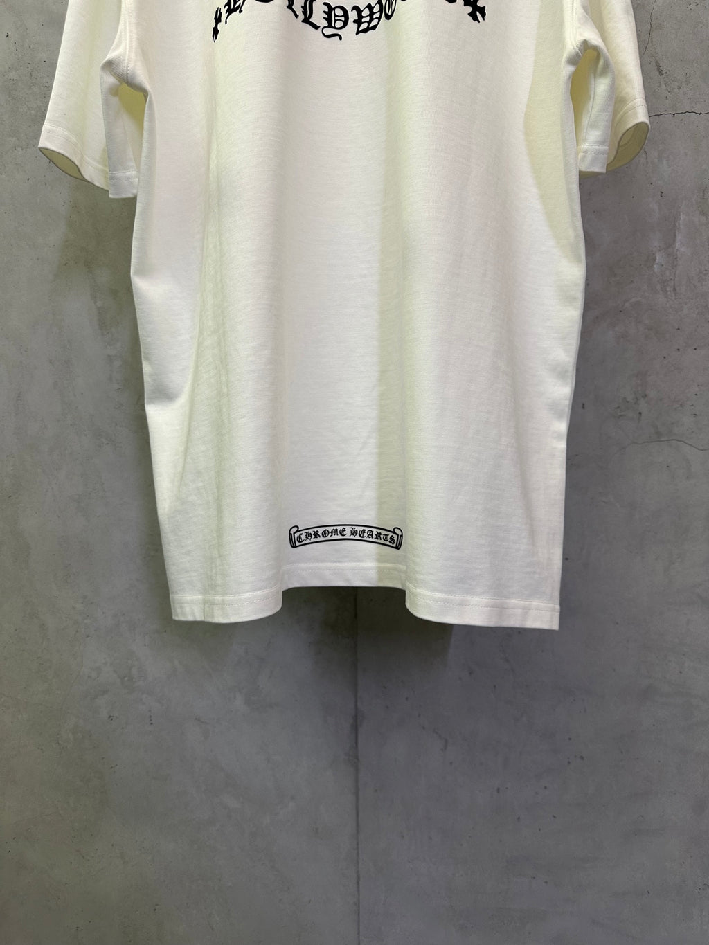 White T-shirt with small black rectangular logo tag near lower hem