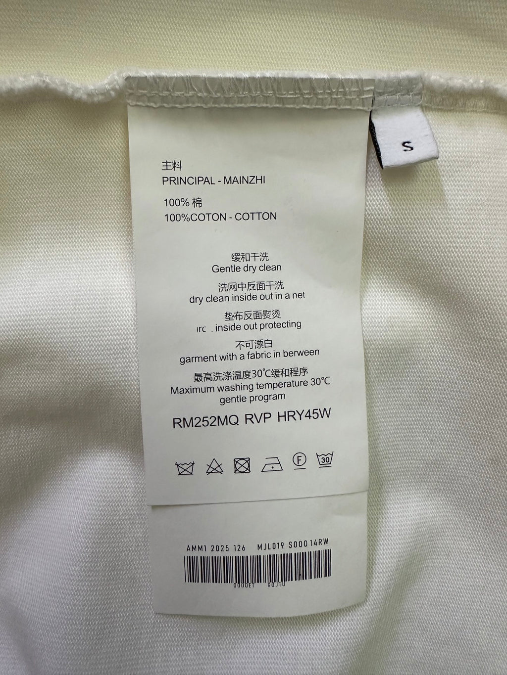White T-shirt care label with size tag and washing instructions inside the collar.