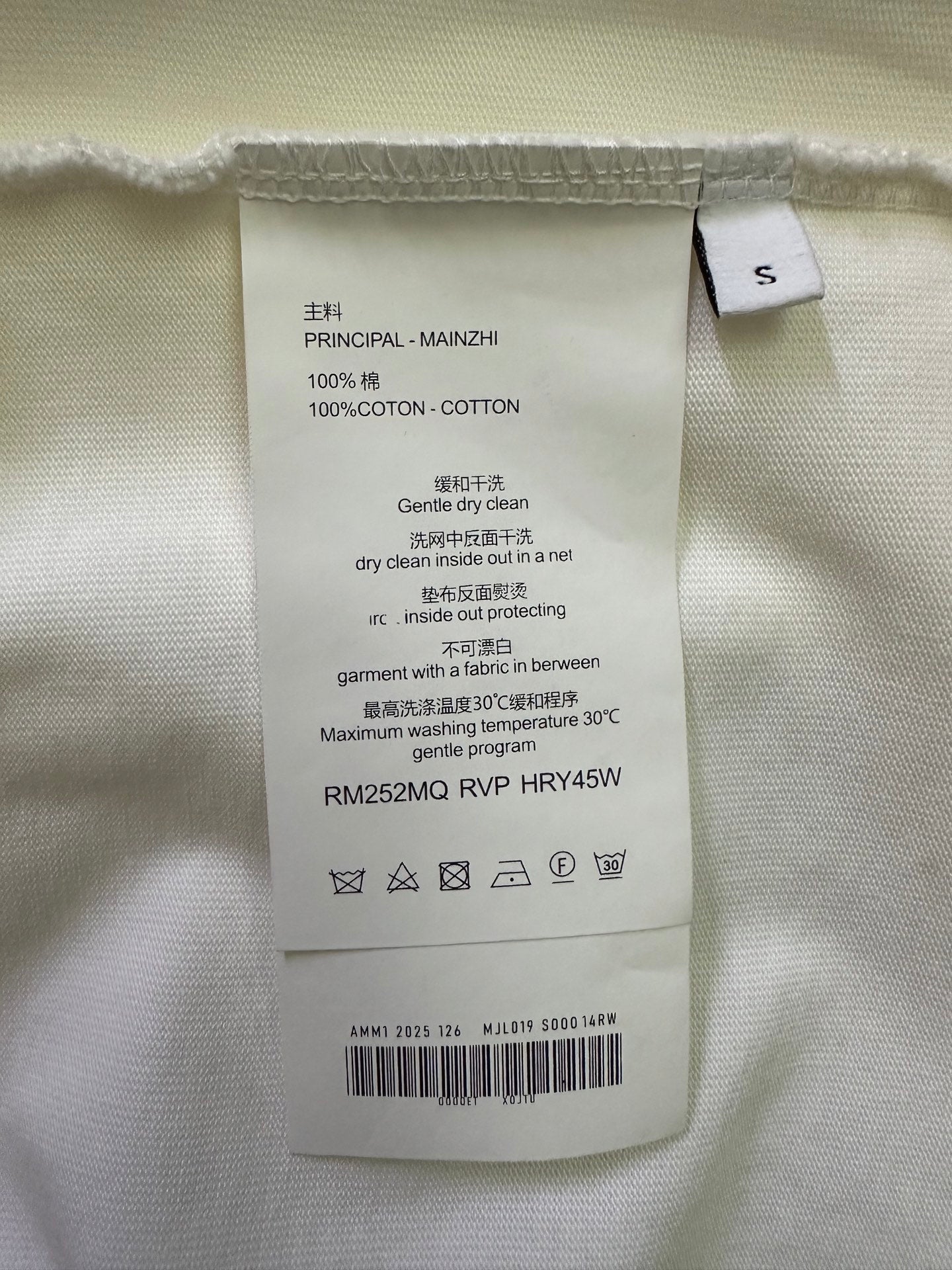 White T-shirt care label with size tag and washing instructions inside the collar.
