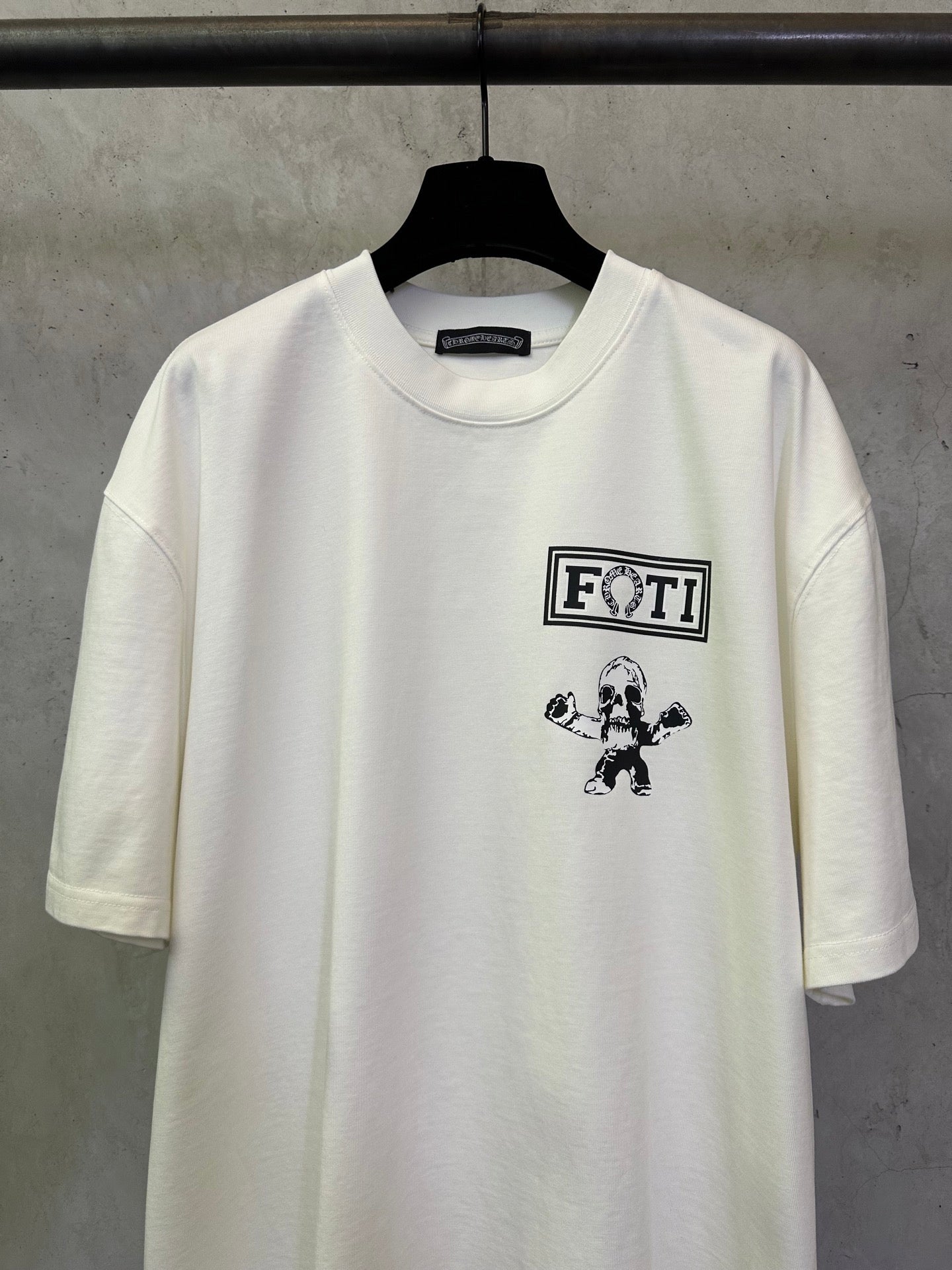 Light short-sleeve T-shirt with FOTI logo and small figure graphic near center