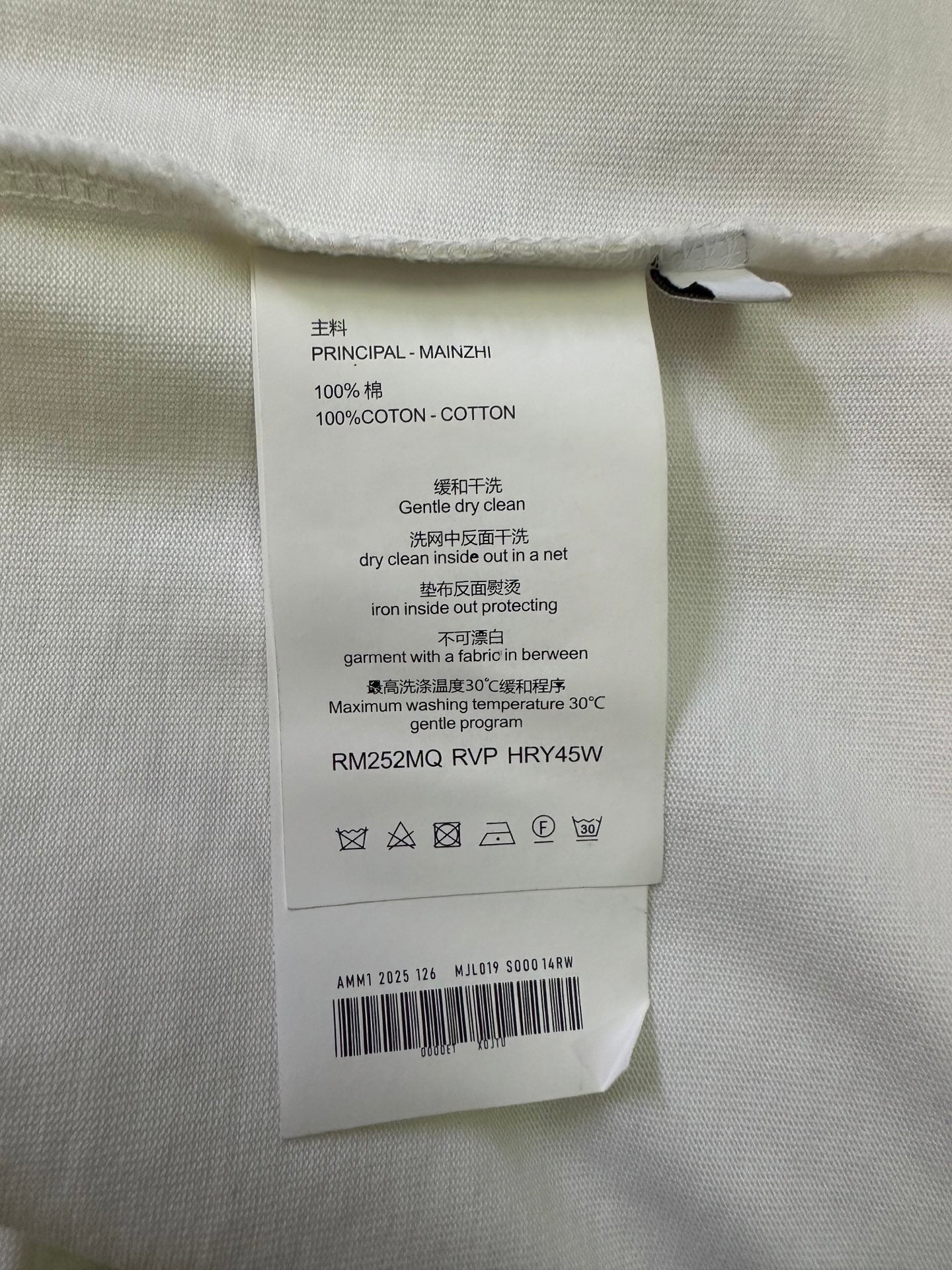 White T-shirt care label tag with text and model details.