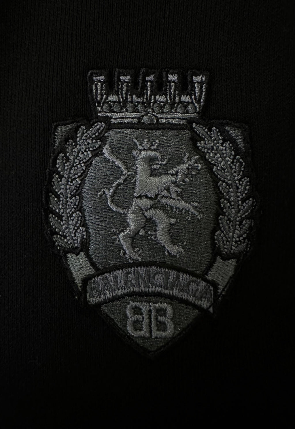 Black fabric patch with Balenciaga crest emblem in gray thread