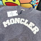 Light gray crewneck sweater with large white MONCLER letter graphic on the chest