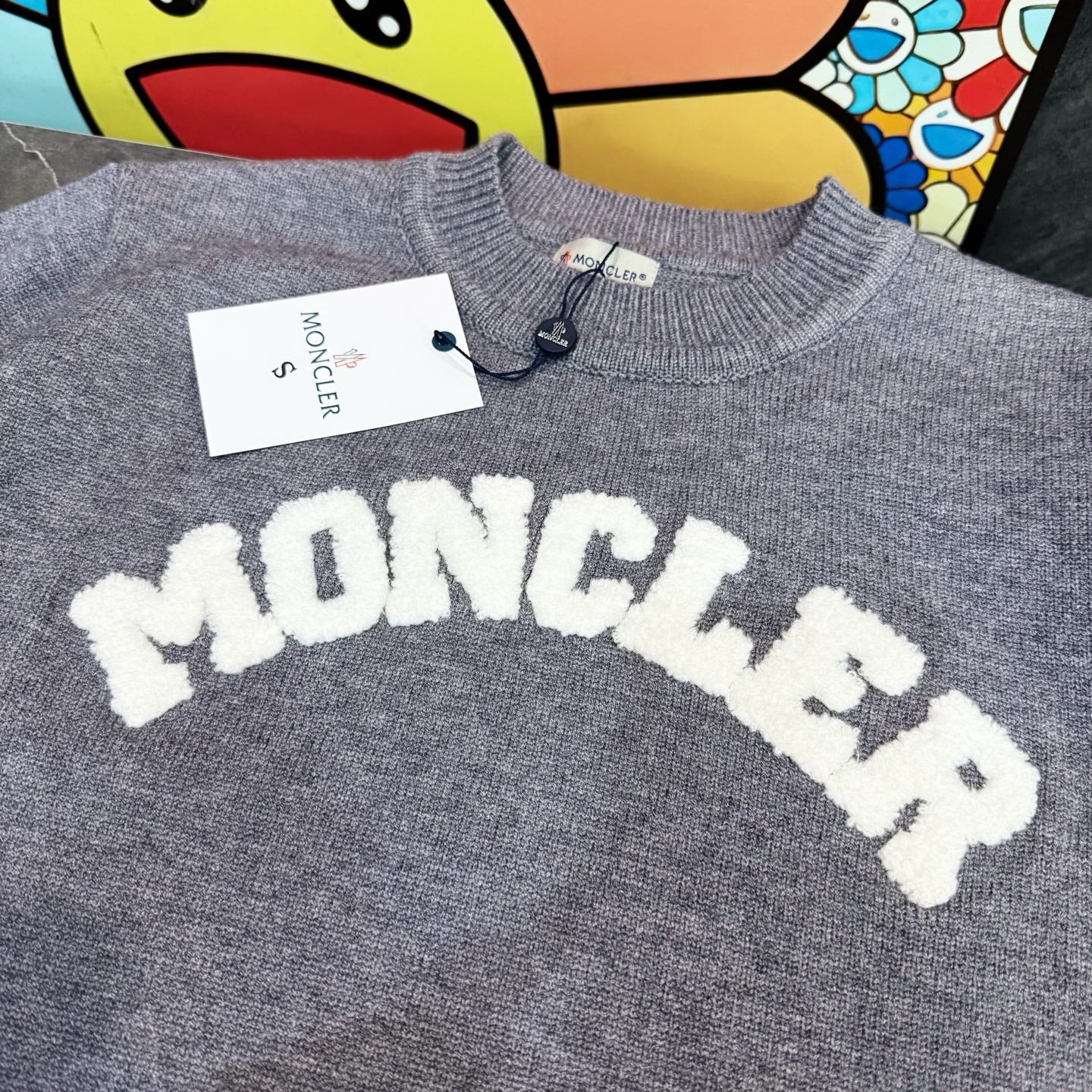 Light gray crewneck sweater with large white MONCLER letter graphic on the chest