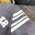 Light gray sweater sleeve with white striped panel and Moncler logo patch