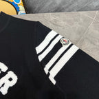 Black sweater sleeve with white striped cuff and Moncler logo patch