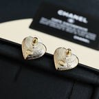 Heart-shaped Chanel stud earrings with gold-tone swirl and small gold emblem