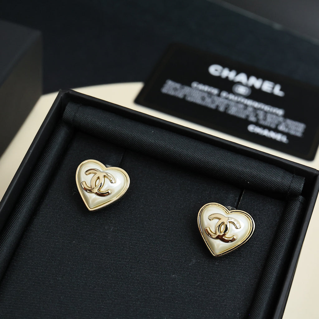 Heart-shaped Chanel stud earrings with white enamel and gold trim in display box