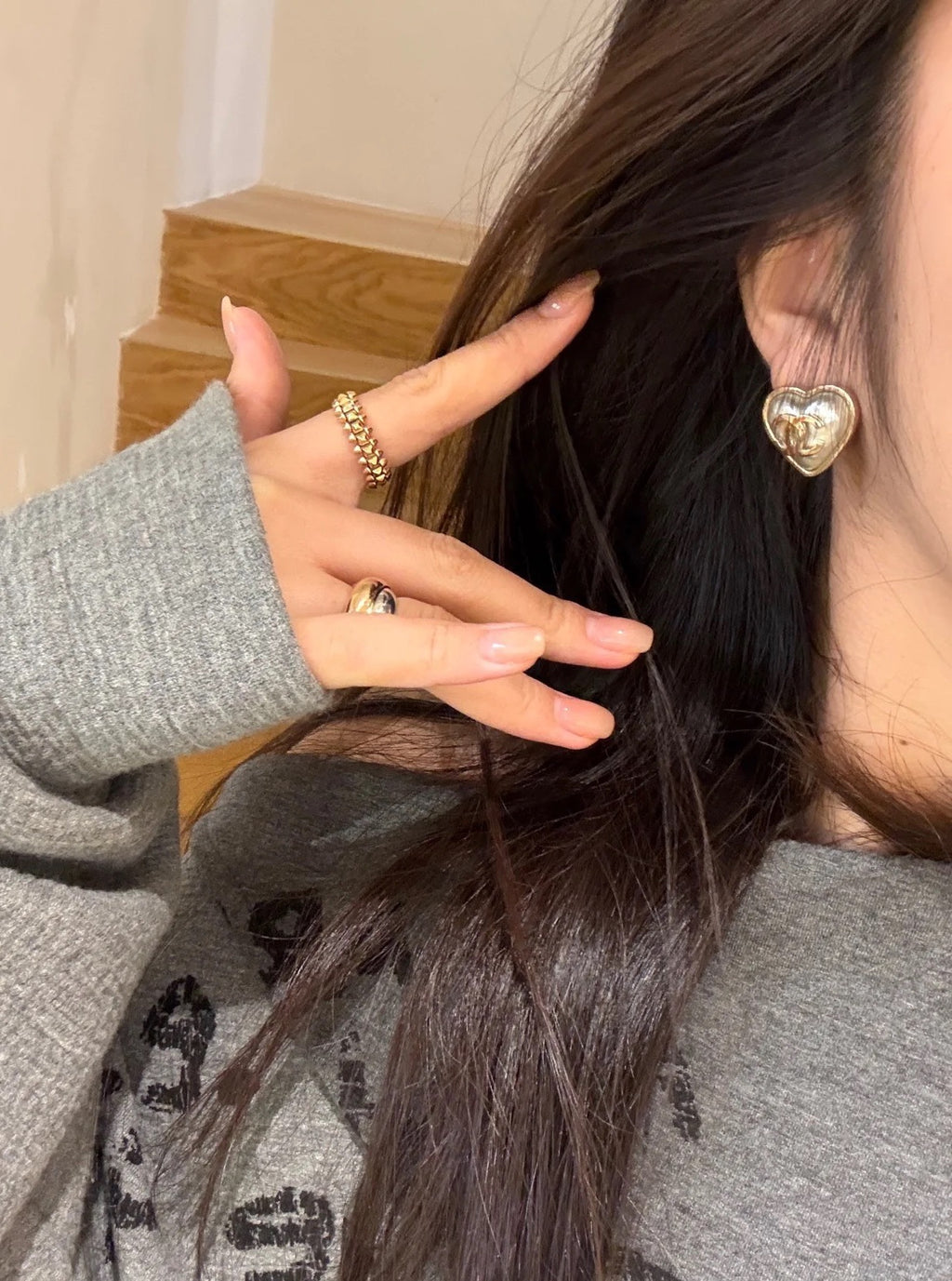 Gold-tone heart stud earrings with Chanel double C logo on ear