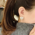 Silver-tone heart stud earrings with Chanel double C logo on ear