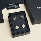 Set of square logo stud earrings arranged in a black jewelry box with certificate cards
