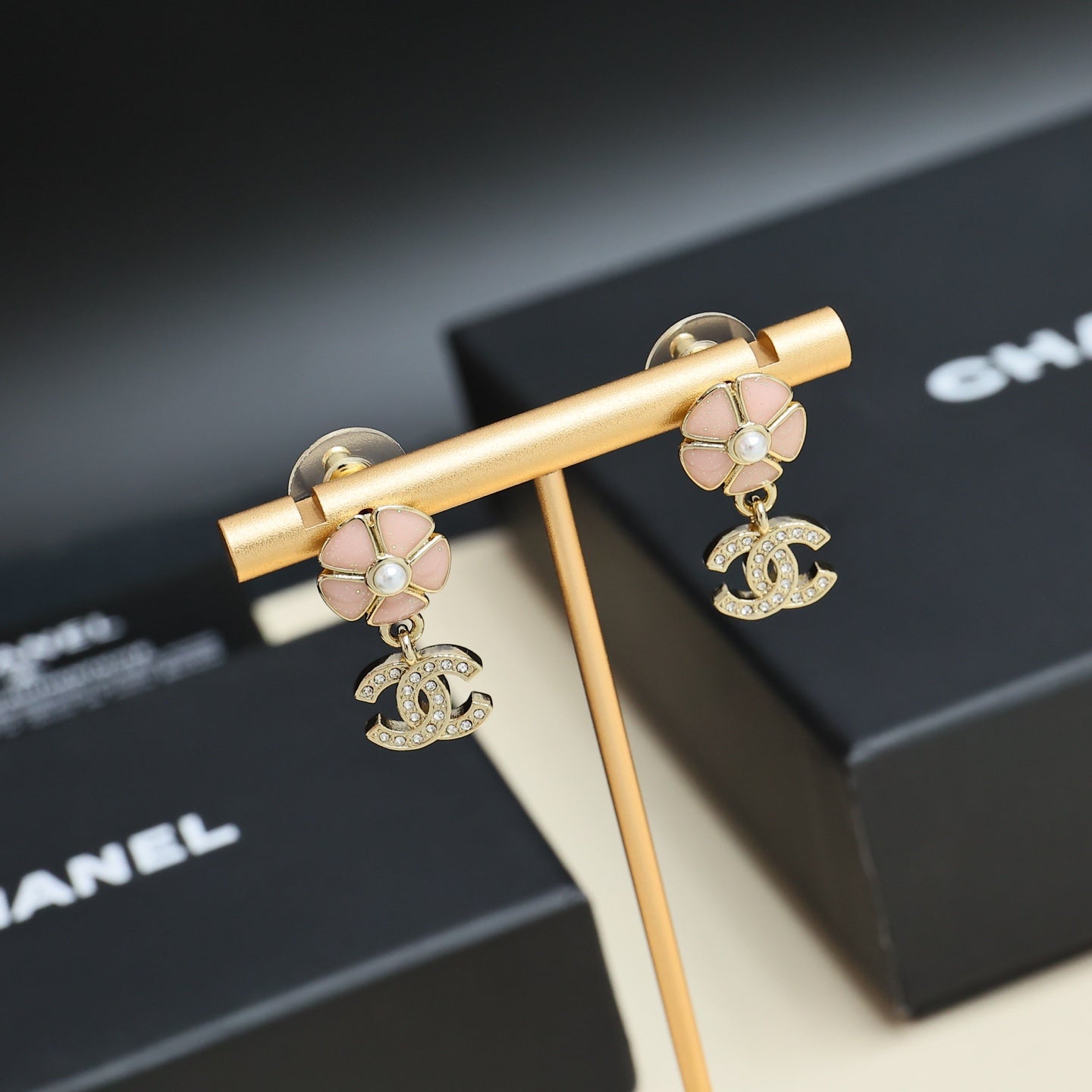 Chanel earrings with gold-tone bar display, pink flower studs, pearls, and CC logo drops