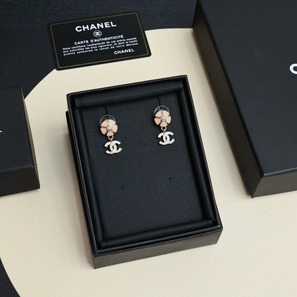 Chanel earrings displayed in black jewelry box, flower stud design with dangling CC logos