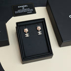 Chanel earrings displayed in black jewelry box, flower stud design with dangling CC logos