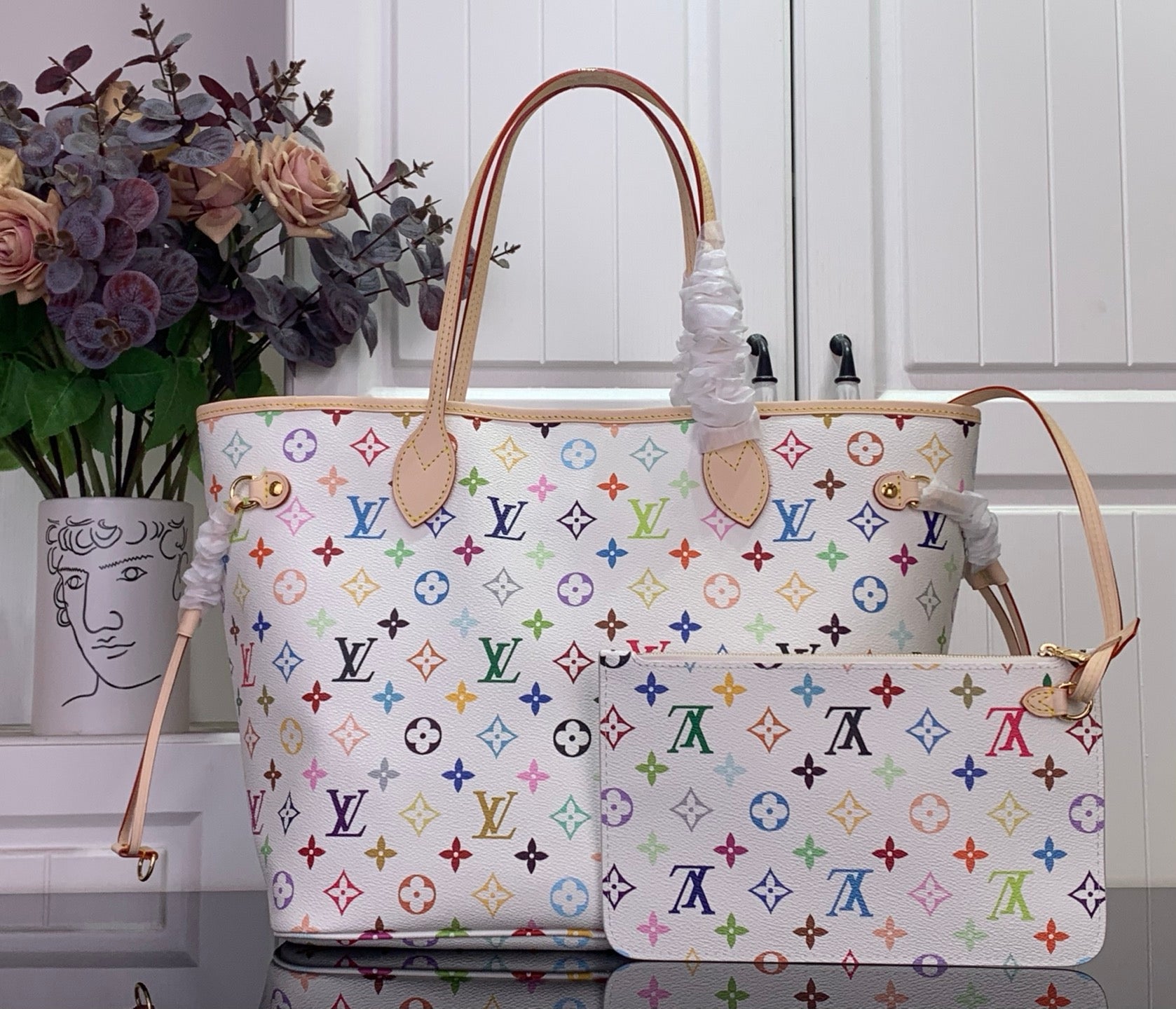 Designer tote bag with multicolor monogram print, center patch pocket and bow accent