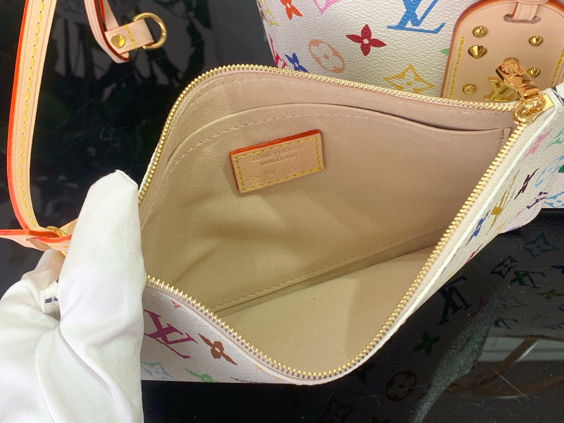 Beige leather bag lining with gold zipper opening and monogram exterior edge