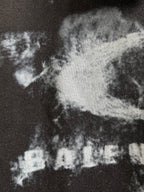 Close-up of white graphic print on dark gray Balenciaga hoodie fabric