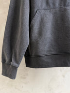 Dark gray hoodie sleeve and front pocket area, showing ribbed hem detail