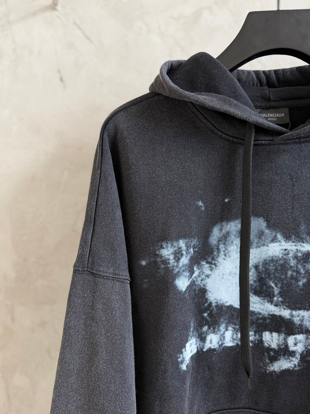 Dark gray hoodie with hood and drawstrings; white splatter graphic across chest and sleeve