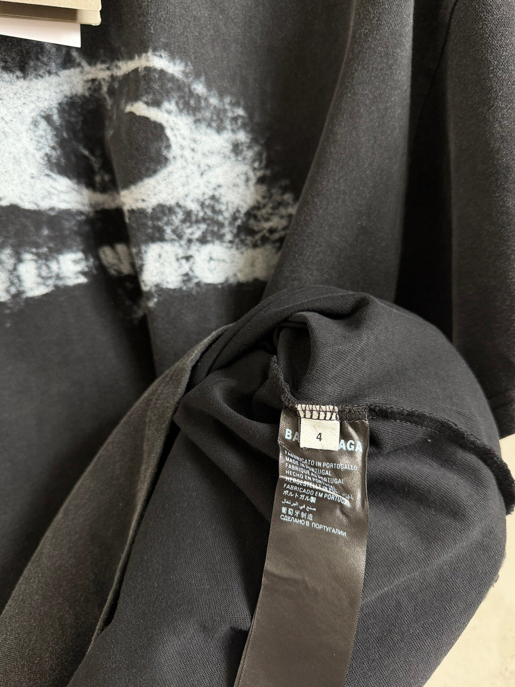 Balenciaga T-shirt close-up of care label and draped fabric on dark gray.