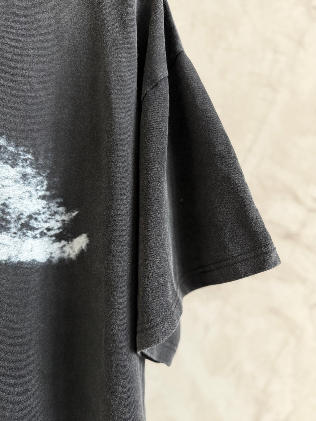 Balenciaga T-shirt sleeve and side seam in dark gray fabric, short cuff hem visible.