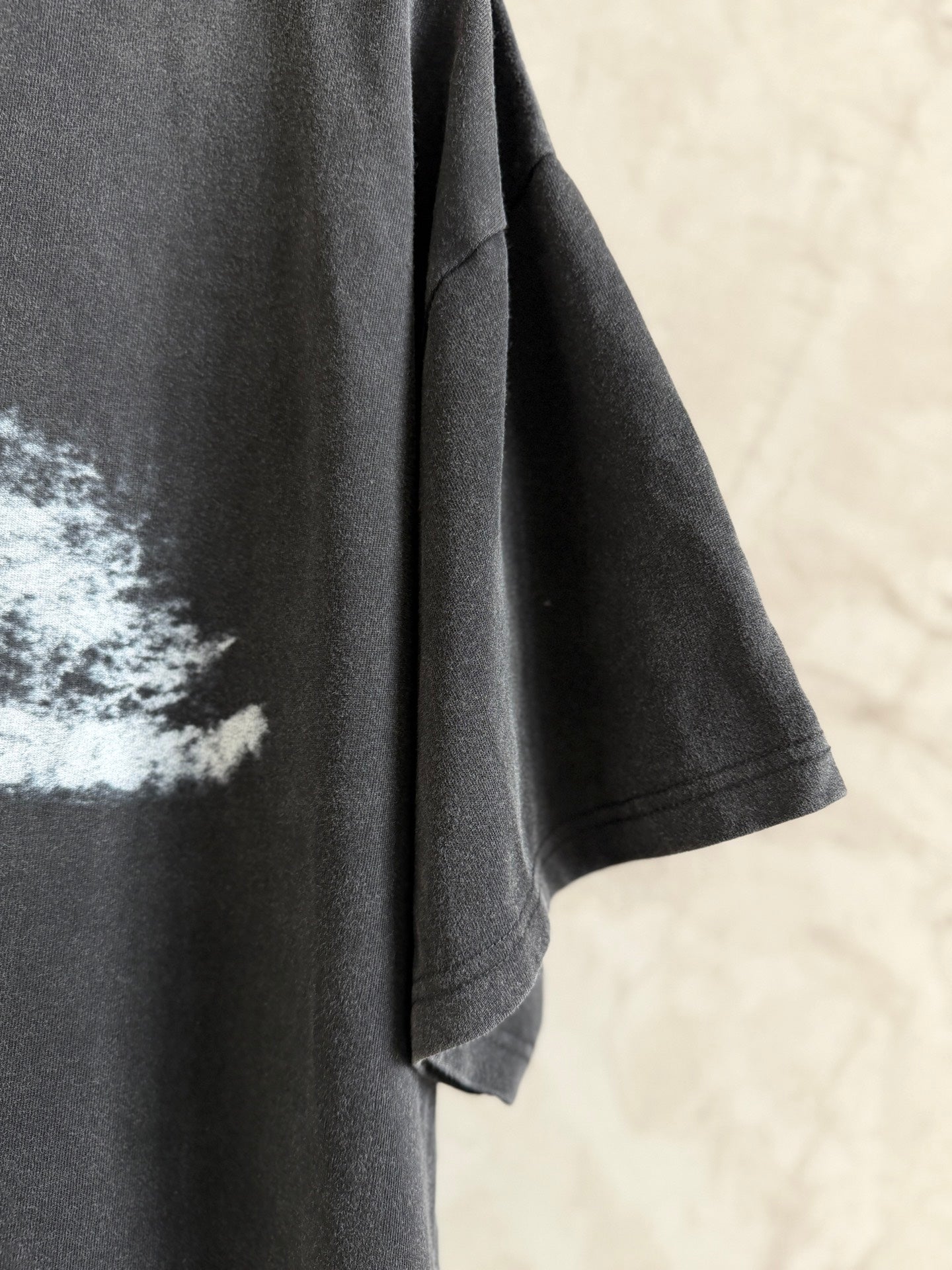 Balenciaga T-shirt sleeve and side seam in dark gray fabric, short cuff hem visible.