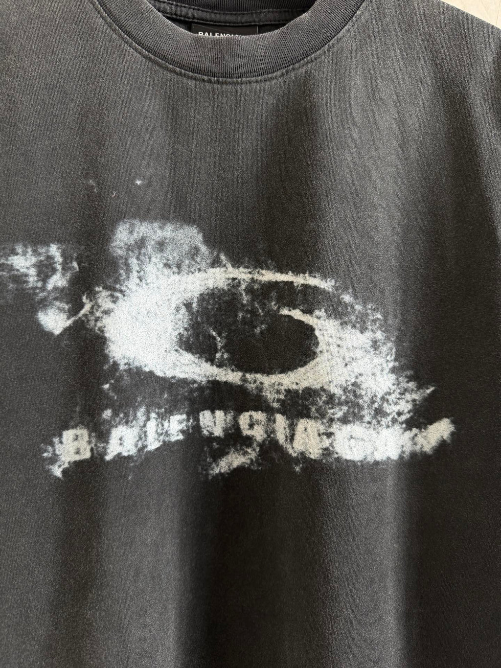Balenciaga T-shirt close-up of white graphic print on dark gray crewneck fabric.