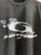 Balenciaga T-shirt close-up of white graphic print on dark gray crewneck fabric.