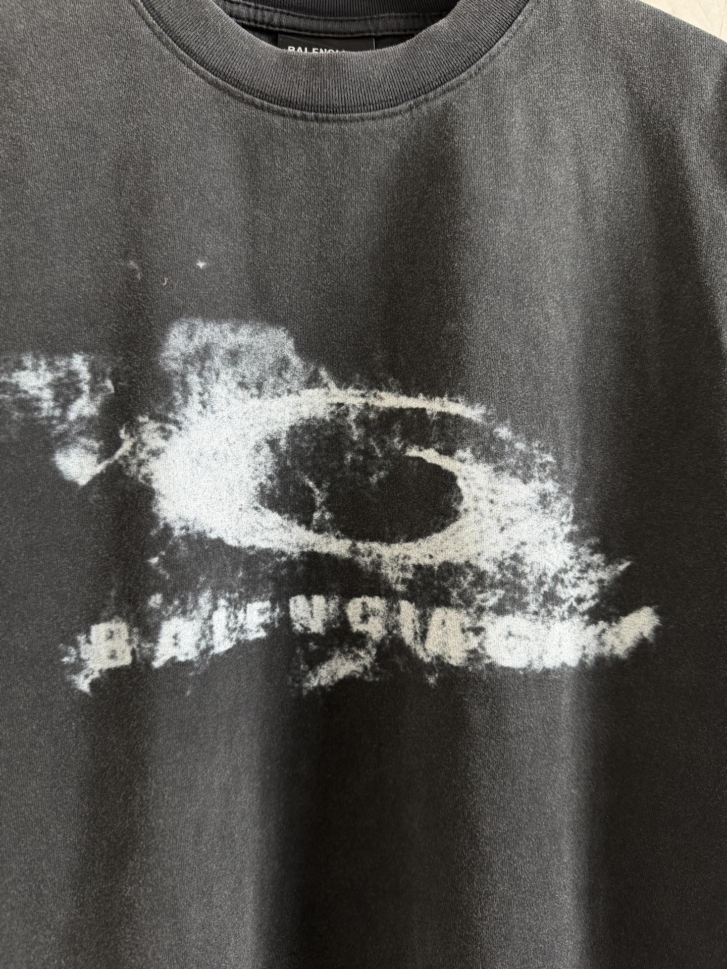 Balenciaga T-shirt close-up of white graphic print on dark gray crewneck fabric.