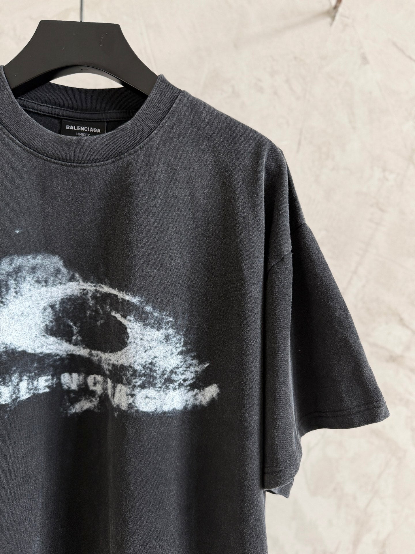 Balenciaga T-shirt angled front view with white graphic print on dark gray, short sleeves.
