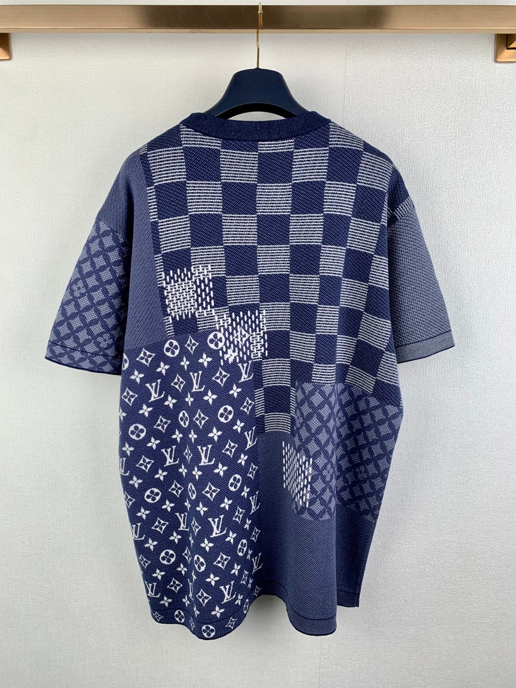 Back view of navy blue short-sleeve shirt with check pattern and monogram graphic panel.