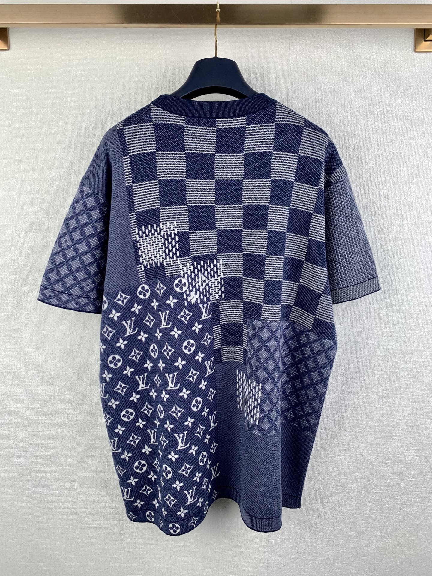 Back view of navy blue short-sleeve shirt with check pattern and monogram graphic panel.