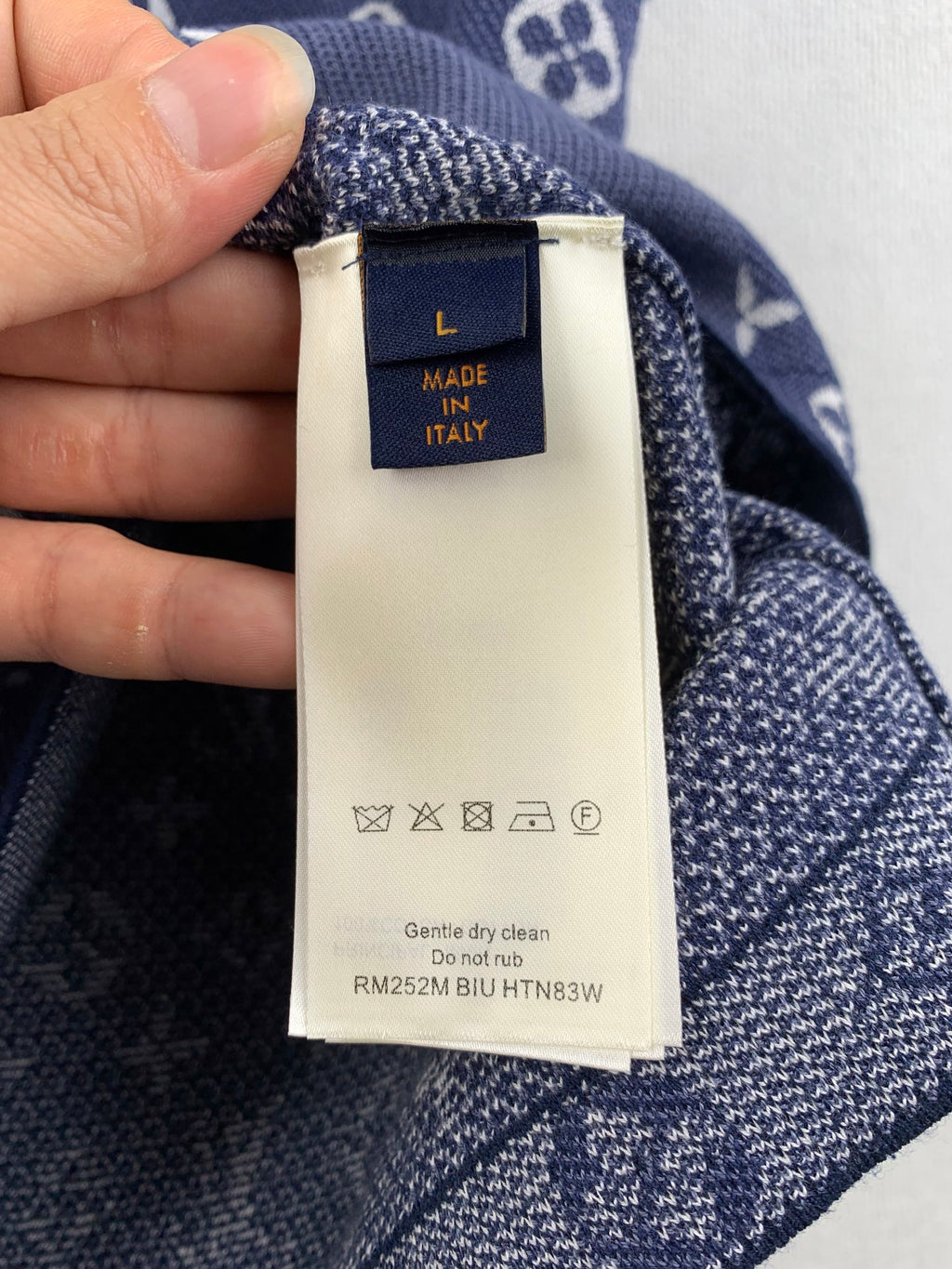 Inside neck label on navy knit shirt: size L, made in Italy, care symbols.