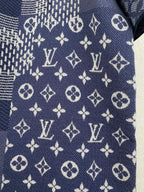 Navy blue short-sleeve fabric close-up with scattered monogram and cross motifs.