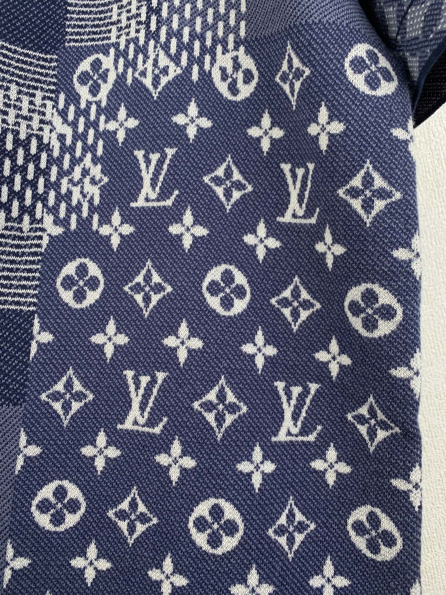 Navy blue short-sleeve fabric close-up with scattered monogram and cross motifs.