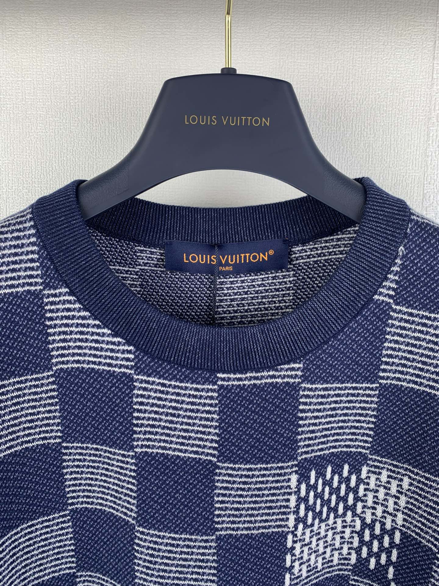 Navy blue short-sleeve shirt close-up with ribbed crew neck and checker patchwork.