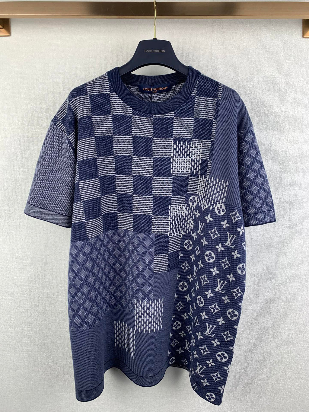 Navy blue short-sleeve shirt with check patchwork and small monogram motifs.