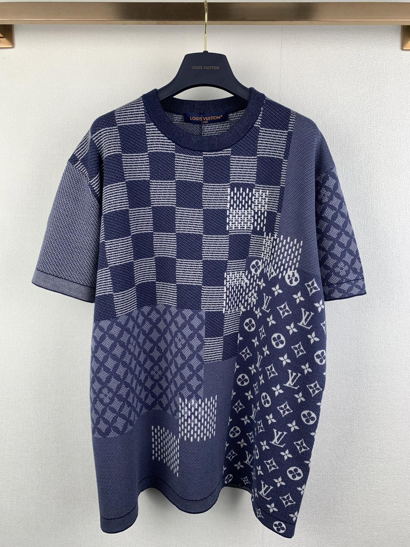 Navy blue short-sleeve shirt with check patchwork and small monogram motifs.