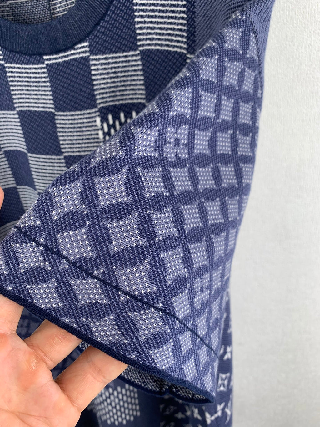 Navy blue short-sleeve shirt sleeve close-up with monogram-style pattern and check grid.