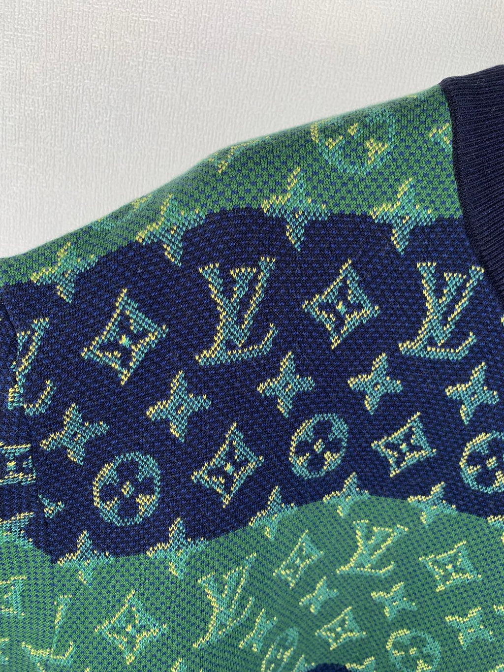 Louis Vuitton knit T-shirt fabric detail in green with navy monogram icons.
