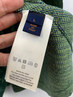 Louis Vuitton clothing label with Made in Italy and care symbols on green fabric.