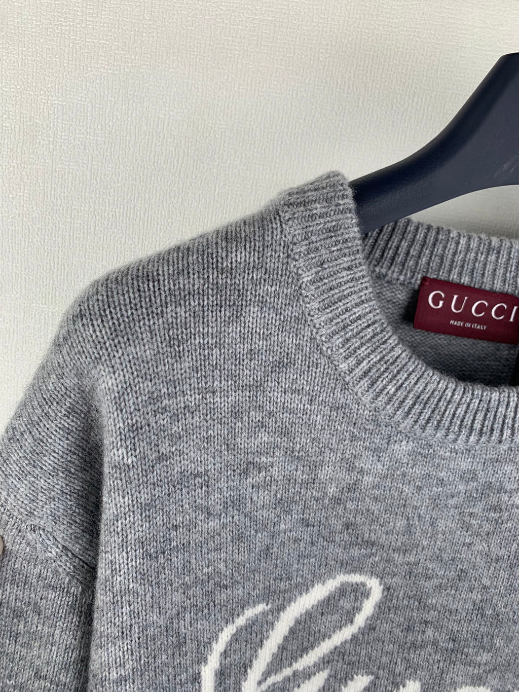 Gray knit sweater neckline detail with Gucci logo tag