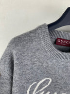 Gray knit sweater neckline detail with Gucci logo tag