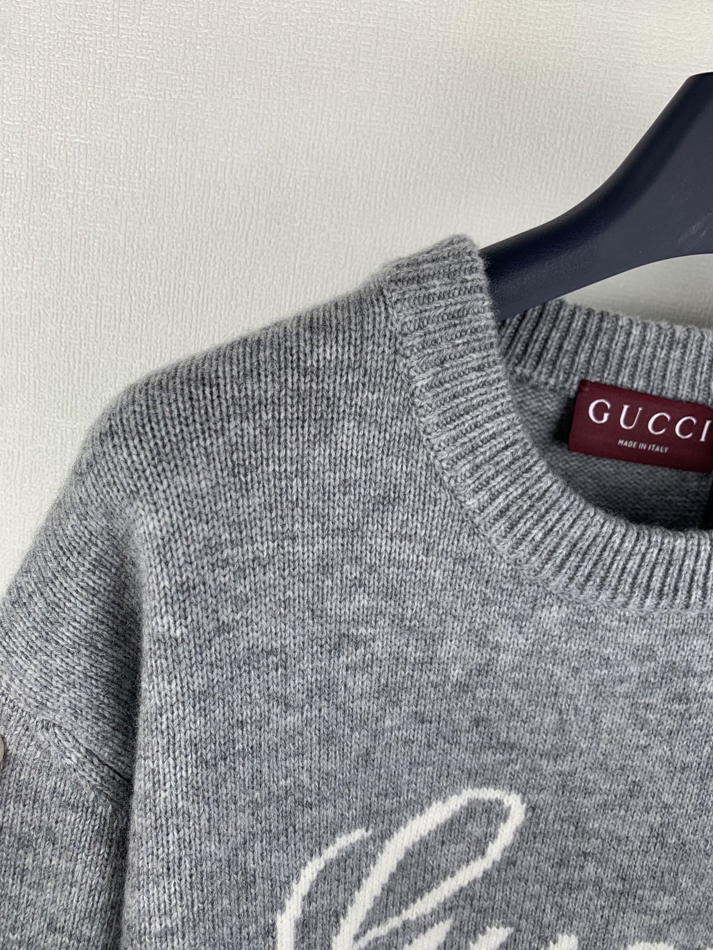 Gray knit sweater neckline detail with Gucci logo tag